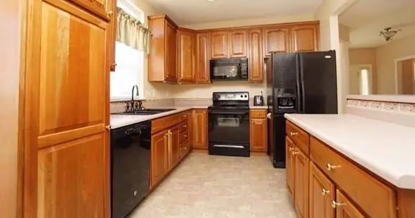 Galley kitchen with honey oak cabinets before respraying