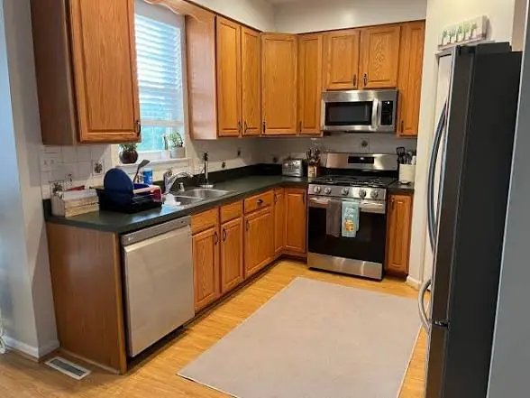 Compact kitchen with mid-brown wood cabinets before respraying