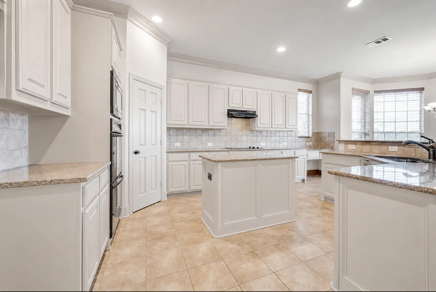 The same island kitchen with cabinets resprayed in warm white